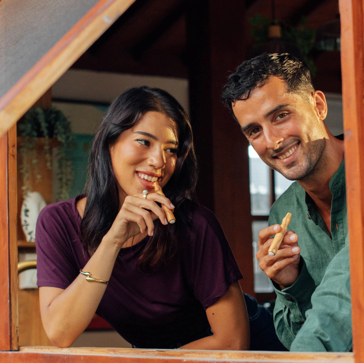 A couple at a window, each holding a Lio flavoured air device